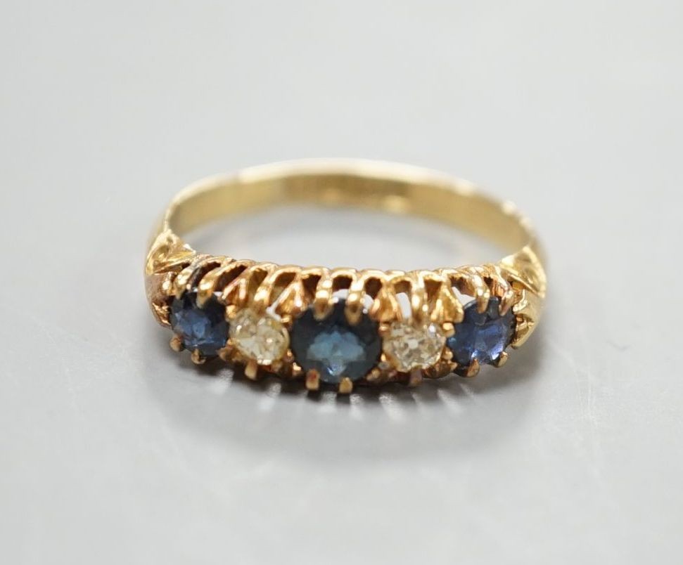 A George V 18ct gold, three stone sapphire and two diamond set half hoop ring, size M, gross 3.1 grams.